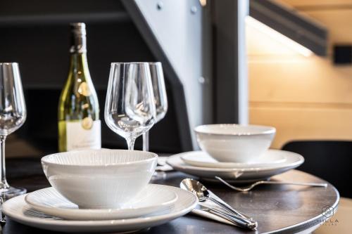 een tafel met borden en glazen en een fles wijn bij Levin Lyhty Bea by Hilla Villas in Kittilä