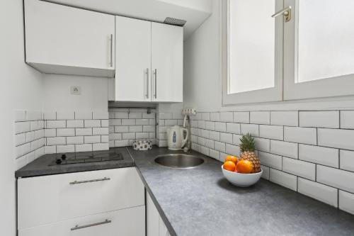 a white kitchen with a bowl of oranges on the counter at BnBNova - 1BR - Les Invalides & Eiffel Tower in Paris