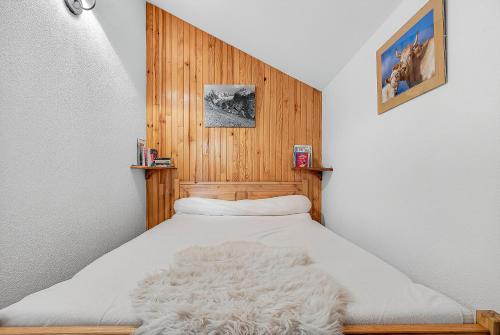 a bedroom with a white bed with a wooden headboard at Appart Tallas Pieds Des Pistes in Ancelle