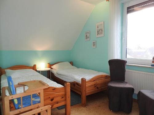 a room with two beds and a chair and a window at Ferienwohnung MeerMoment in Wangerland