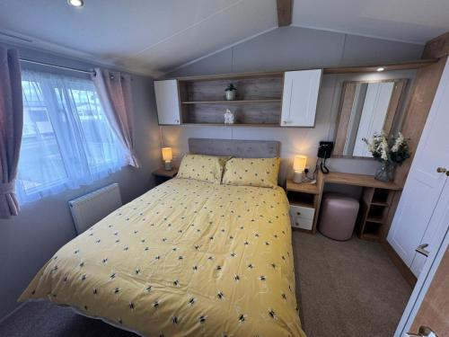 a bedroom with a bed with a yellow comforter at Fantasy Island - Eastgate E6 - The Sierra with Hot Tub - Coastal Caravan Breaks in Ingoldmells