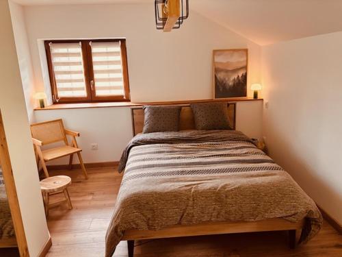 ein Schlafzimmer mit einem Bett und einem Stuhl und einem Fenster in der Unterkunft Le Chantoiseau in Muhlbach-sur-Munster