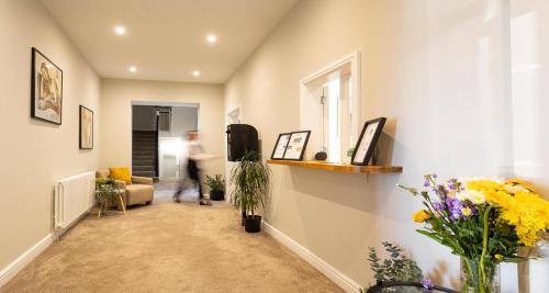 a person walking through a living room with flowers at The Clarence Gardens Hotel, BW Signature Collection in Scarborough