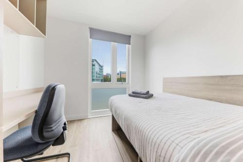 a bedroom with a bed and a chair and a window at Brand New Ensuites In Central Leeds in Leeds