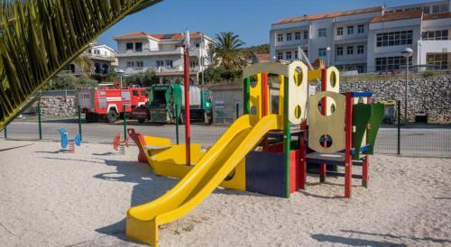 un parque infantil con un tobogán en la arena en Apartments Iva i Marko, en Marina