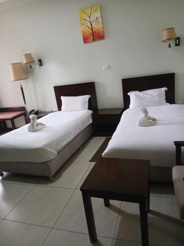 Dos camas en una habitación de hotel con una mesa. en Kitsel Hotel, en Bahir Dar