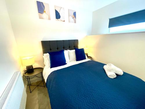 a bedroom with a large bed with blue pillows at The Townhouse Collection 2BR Close To City Centre in Cardiff
