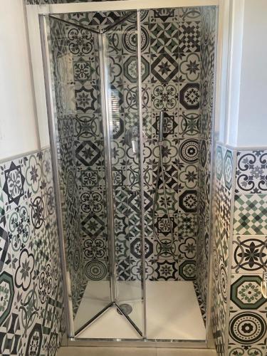 a glass shower in a room with patterns on the wall at La Logghia rooms in Avola