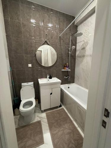 a bathroom with a toilet and a sink and a tub at Prestige Ap in Ustʼ-Kamenogorsk