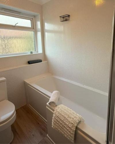 a bathroom with a tub and a toilet and a window at Spacious 3 Bed Apartment In Central Horsham in Roffey