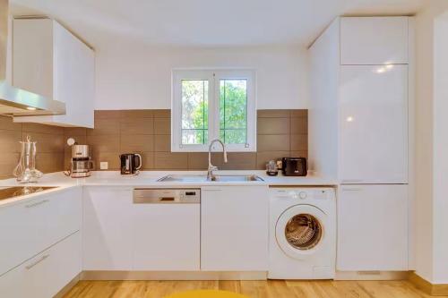 a kitchen with white cabinets and a washing machine at Pine Cliffs Village in Albufeira