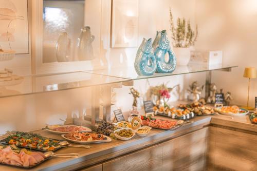 Un buffet con muchos platos de comida y jarrones. en Strandhotel Kärntnerhof, en Pörtschach am Wörthersee
