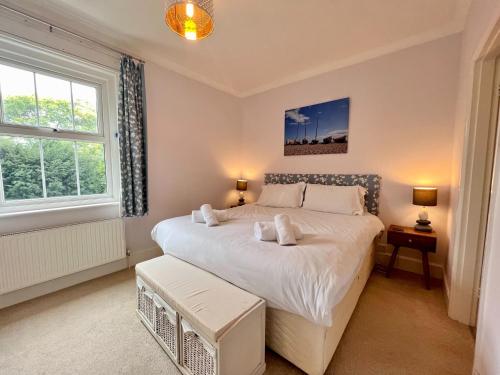 a bedroom with a large white bed with two windows at Thimble Cottage in Sidmouth