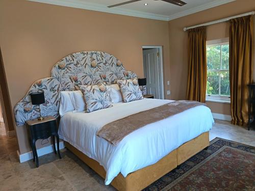 a bedroom with a large bed with a large headboard at La Jolie Dauphine Guest House in Franschhoek