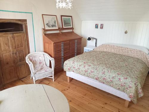 a bedroom with a bed and a chair and a table at maison bretonne proche plages et commerces in Plobannalec-Lesconil