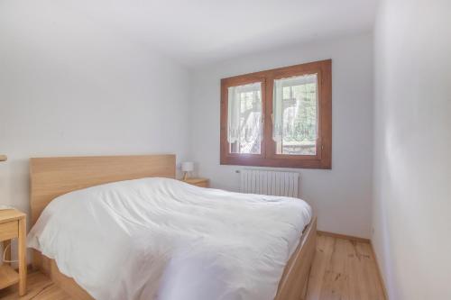 a white bedroom with a bed and a window at Ruoibes 17 in San Vito di Cadore