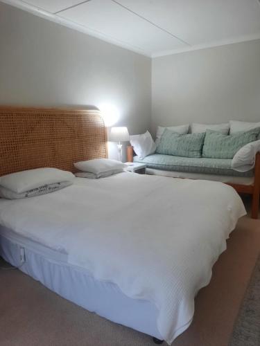 a bedroom with a large white bed and a couch at StruisPlace in Struisbaai