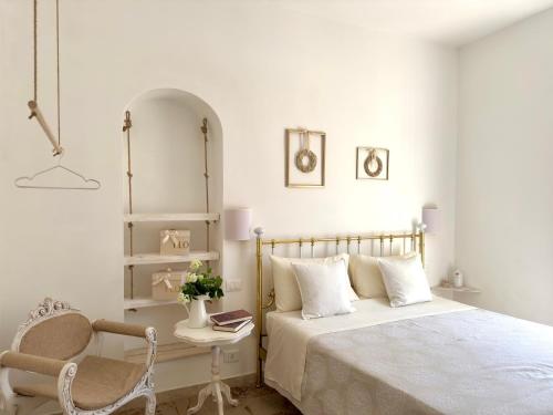 ein weißes Schlafzimmer mit einem Bett und einem Stuhl in der Unterkunft Eldoh in Bernalda