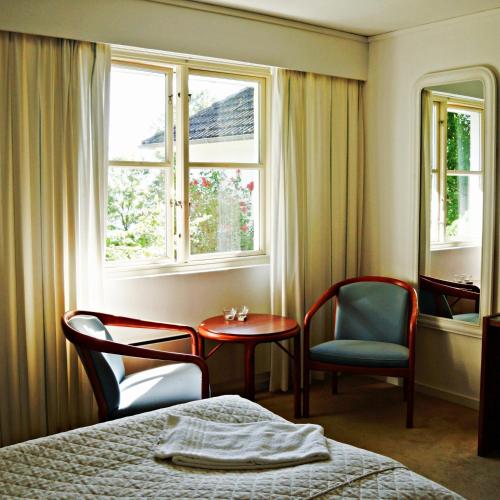 a bedroom with a bed and two chairs and a window at Johanneberg in Vordingborg
