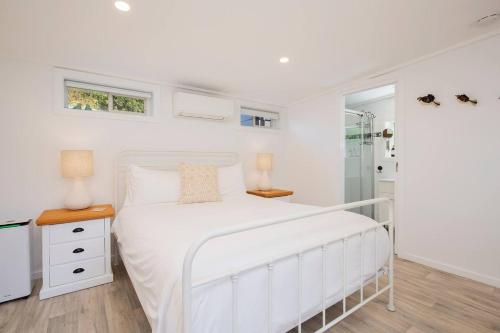 a white bedroom with a white bed and a window at Fairy Nook - Charming Granny Flat with Shared Garden in Mayfield