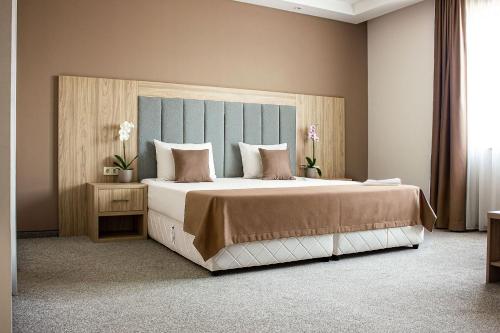 a bedroom with a large bed with a blue headboard at SPS Hotel in Plovdiv