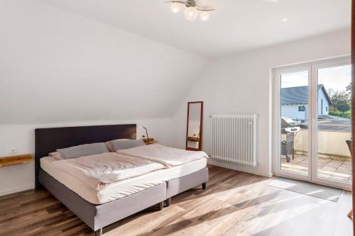 ミュールハイムにあるFerienwohnung am Bachの白いベッドルーム(ベッド1台、バルコニー付)