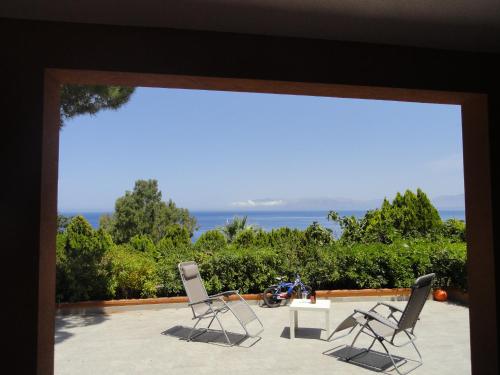 two chairs and a table on a patio with the ocean at Piccola Baia in Scopello