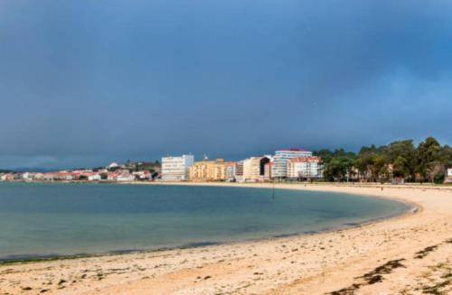 Una vista de una playa con edificios al fondo. en Nordés, en Vilagarcía de Arousa