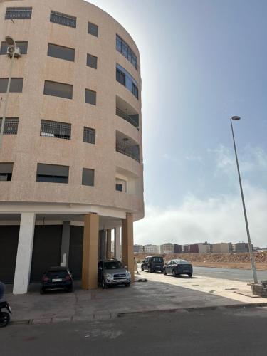 a building with cars parked in a parking lot at Spacious Apartment in heart of Agadir in Agadir