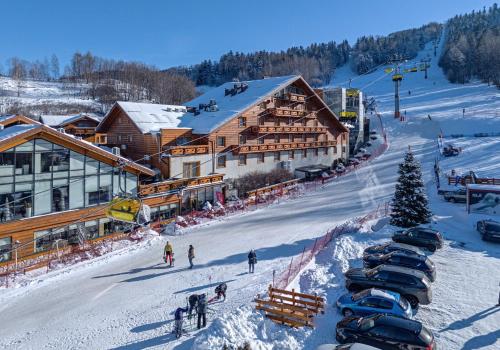 a ski lodge with cars parked in the snow at Hotel Meta Resort & Vine SPA in Szczyrk