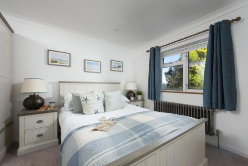 a bedroom with a bed with blue curtains and a window at Chyvounder in Sennen