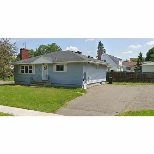 a blue house with a porch and a driveway at Lynn's Place in Moncton