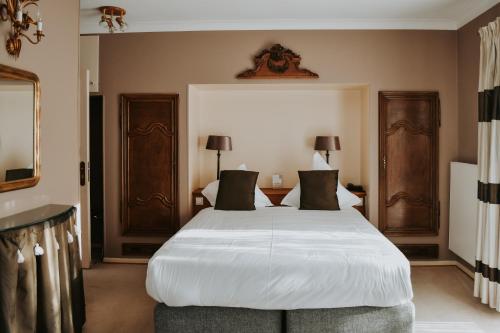 a bedroom with a large white bed with black pillows at Hotel de la Gaichel in Eischen