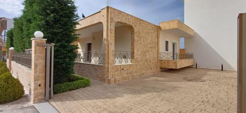 a large brick house with a balcony on a courtyard at Blue Ark Aigeira Flat & Studio in Aíyira