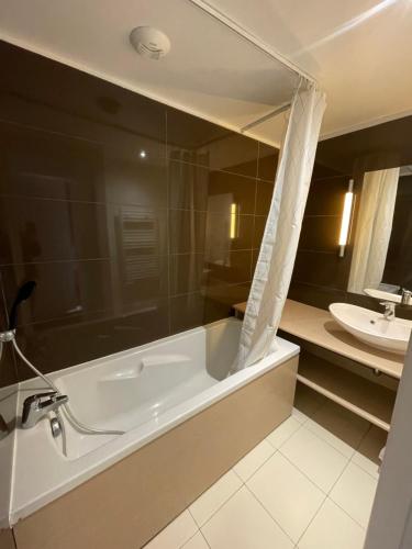 a bathroom with a bath tub and a sink at T3 Terrasse Piscine Sauna Spa Jausiers Magnans in Jausiers