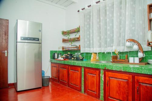 eine Küche mit einem Edelstahlkühlschrank und grünen Arbeitsplatten in der Unterkunft Cottage Haven Villa in Galle