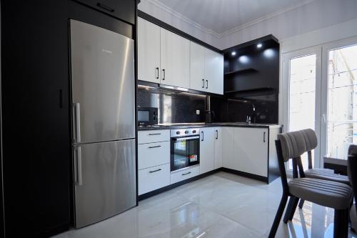 a kitchen with white cabinets and a stainless steel refrigerator at ChioSmart Town Apartments in Chios