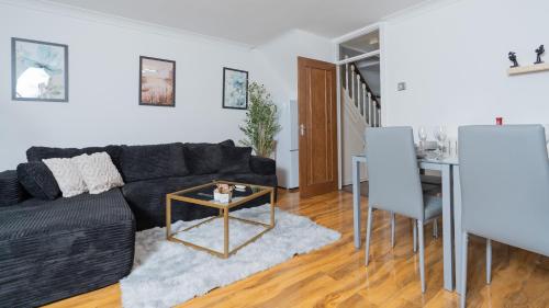 a living room with a black couch and a table at Open Mind Property - 3 Bed Home with Free Parking in Portsmouth