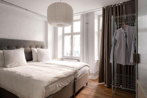 a bedroom with a bed and a window with a suit on a rack at Chic city pad with handpainted art in great location by Daniel&Jacob's in Copenhagen