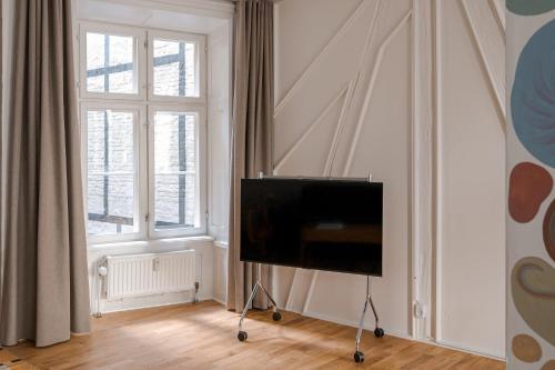 a flat screen tv in a room with two windows at Chic city pad with handpainted art in great location by Daniel&Jacob's in Copenhagen