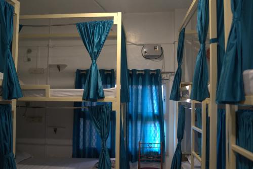 Una habitación con literas con cortinas azules y un espejo. en Kashi Vibes Hostel, en Varanasi