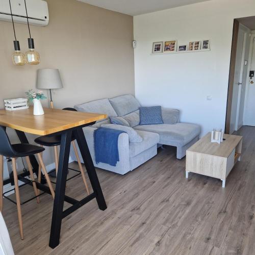 ein Wohnzimmer mit Tisch und Couch in der Unterkunft Apartamento con vistas al mar y montaña - Piscina in Santa Susanna