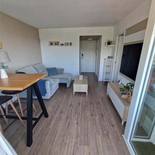 ein Wohnzimmer mit Sofa und Tisch in der Unterkunft Apartamento con vistas al mar y montaña - Piscina in Santa Susanna