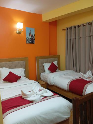 deux lits dans une chambre aux murs orange dans l'établissement Rambler's Hotel, à Katmandou