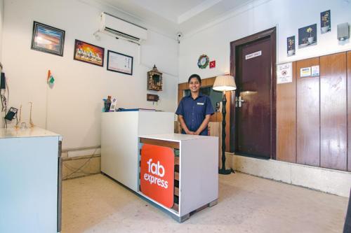 a man is standing next to a job services counter at FabHotel JDM Residency in Gurgaon