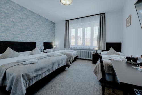 a bedroom with two beds and a desk and a window at 7Days B&B in Bratislava