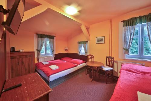 a bedroom with a red bed and a table at Hotel Diana in Špindlerův Mlýn