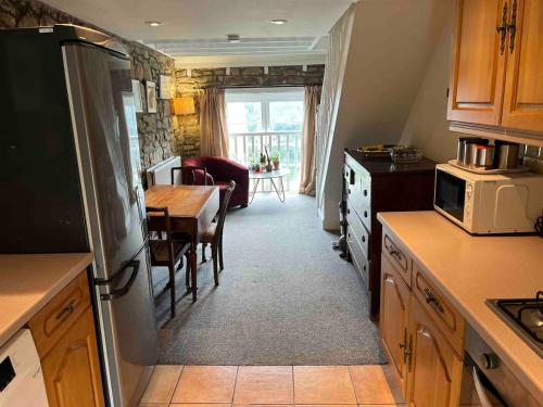 a kitchen with a refrigerator and a table and a dining room at 2 bed apartment & parking, Carlops,10 mins drive Edinburgh bypass in Carlops