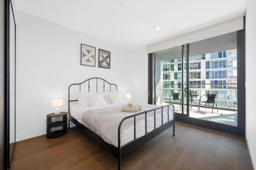 a white bedroom with a bed and a large window at AccorView Luxury 1BR Suite Pool Gym Parking in Sydney
