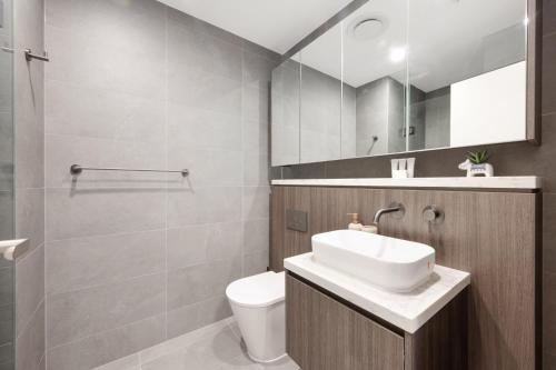 a bathroom with a sink and a toilet at AccorView Luxury 1BR Suite Pool Gym Parking in Sydney